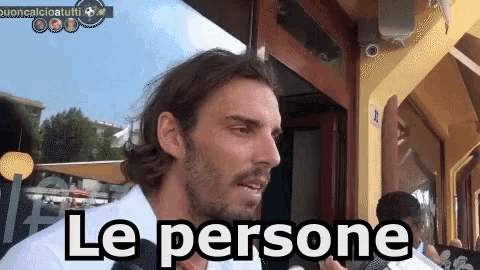 a man in a white shirt says le persone in front of a building