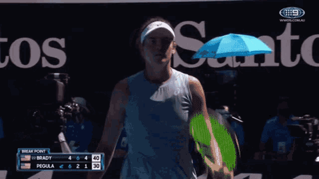 a woman holding a blue umbrella in front of a sign that says santos