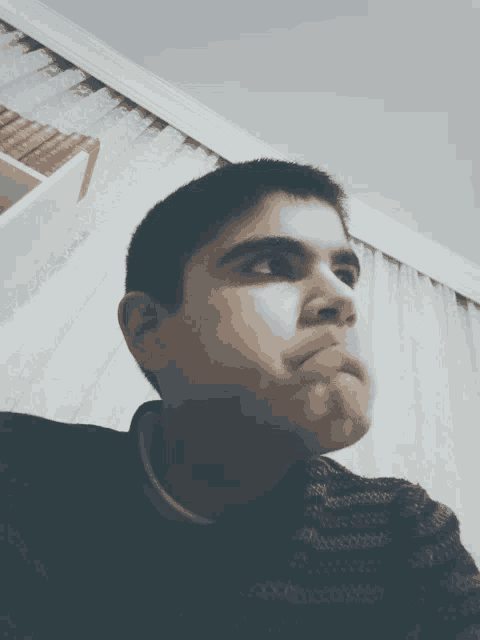 a young man making a funny face in front of a bookshelf