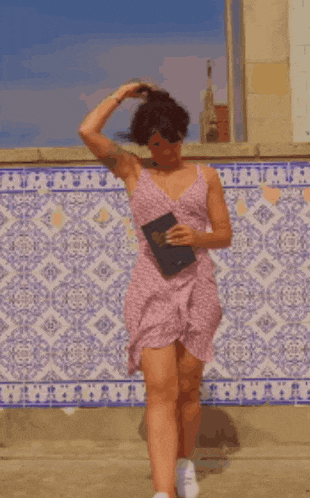 a woman in a pink dress is dancing with a book in her hand