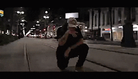 a man is kneeling down on a sidewalk in a city at night