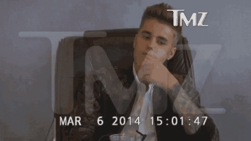 a man covering his face in front of a screen that says tmz on it