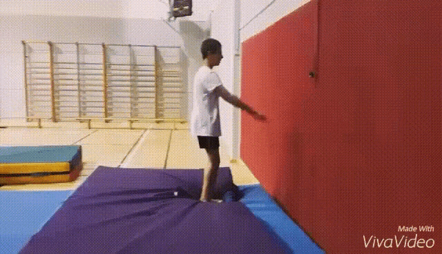 a boy is jumping on a trampoline in a gym .