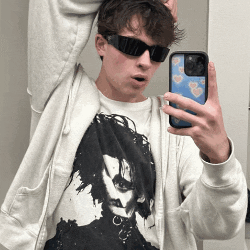 a young man wearing sunglasses takes a picture of himself with his phone