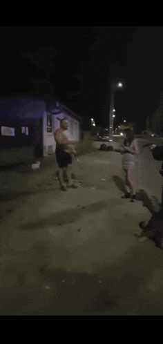 a group of people are playing with a dog in a dark street
