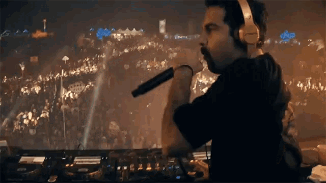 a man wearing headphones is holding a microphone in front of a crowd of people