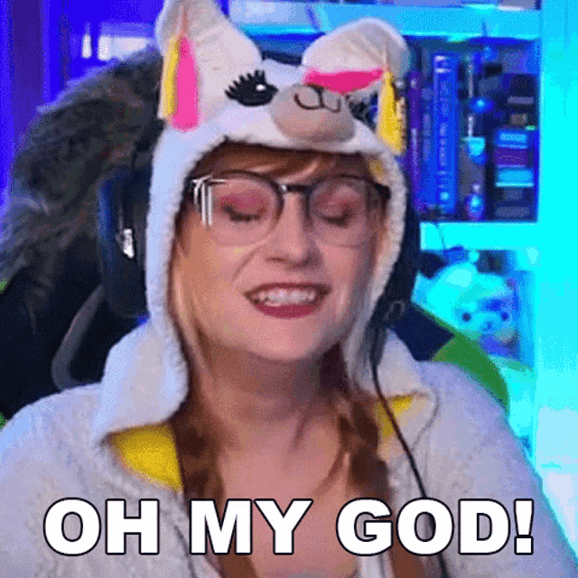 a woman wearing a unicorn hat and glasses is smiling and saying `` oh my god ! ''