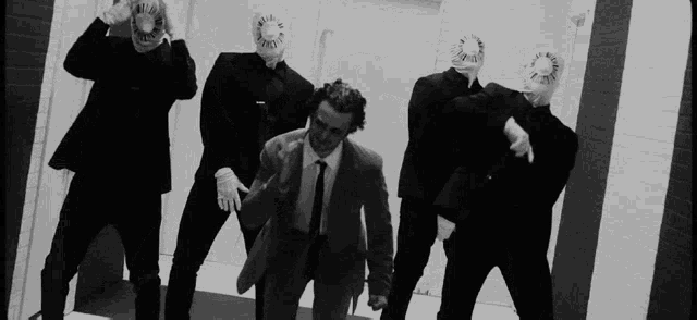 a group of men in suits and masks are standing in a room .