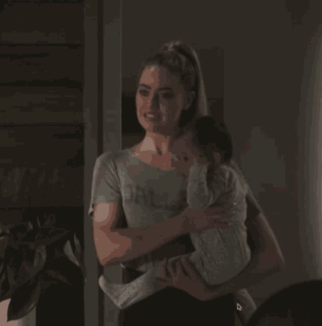 a woman holding a baby wearing a shirt that says dallas on it