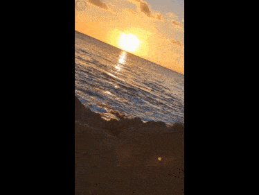 a sunset over a body of water with a smiley face on the bottom left
