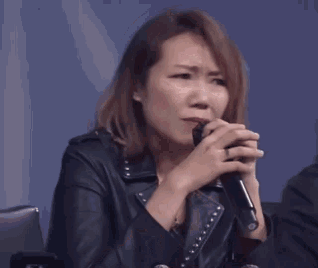 a woman singing into a microphone with chinese characters above her head