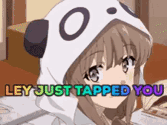 a girl wearing a panda hoodie is sitting at a table with a book .