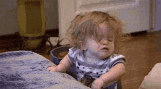 a baby is crying while sitting on a couch in a room .