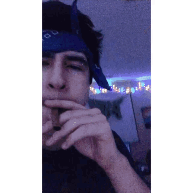 a man with a blue bandana on his head is smoking a cigar