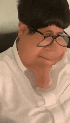 a man wearing glasses and a white shirt is making a face