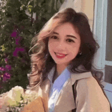 a young woman is holding a bouquet of flowers and smiling .