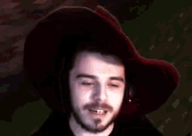 a man with a beard and mustache is wearing a large red hat .