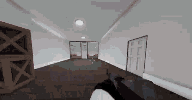a person is holding a gun in a hallway with a box in the background .