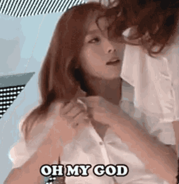 a woman in a white shirt is being kissed by another woman and the words `` oh my god '' are written on the screen .