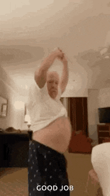 an older man is dancing in a living room with his shirt off and his belly exposed .