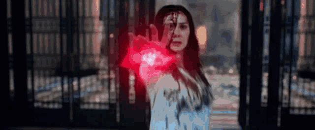 a woman is holding a red glowing object in her hands .