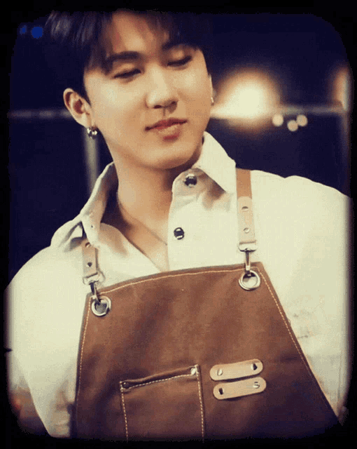 a young man wearing a brown apron with a white shirt on