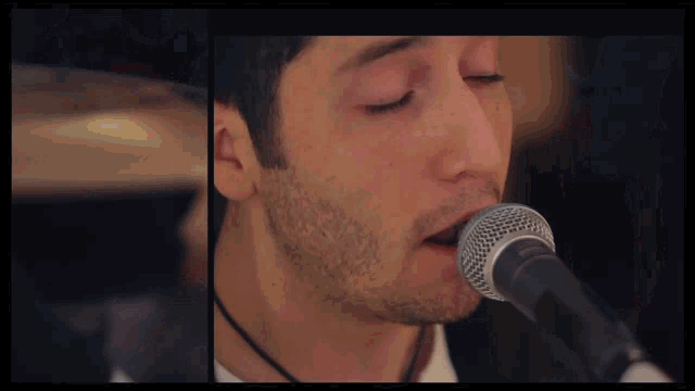 a close up of a man singing into a shure microphone