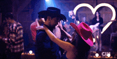 a man in a cowboy hat kisses a woman in a pink hat