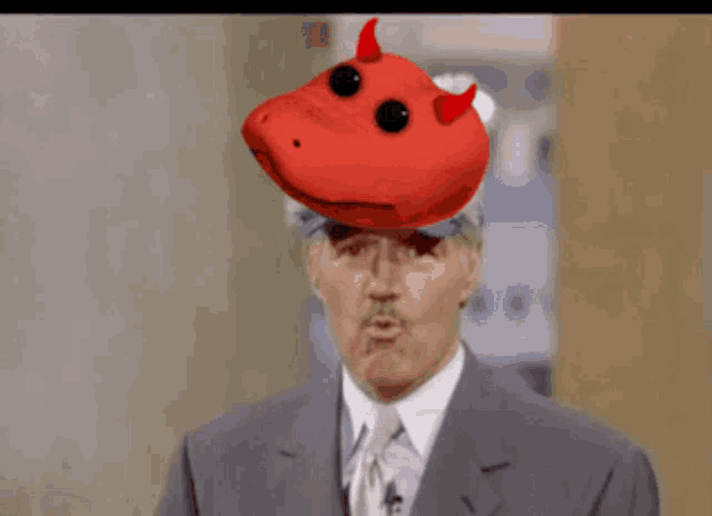 a man in a suit and tie has a stuffed animal on his head