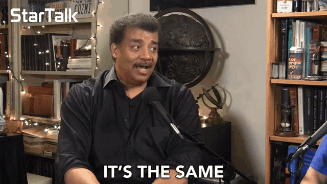 a man talking into a microphone with the words it 's the same behind him