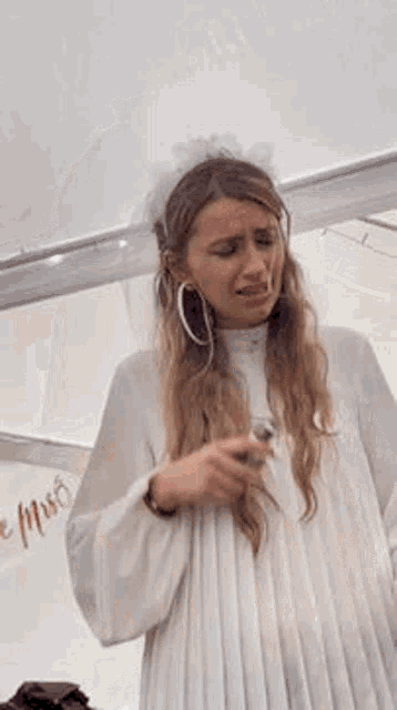 a woman in a white dress and veil is crying and holding a glass of wine .