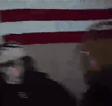 a blurry picture of a man standing in front of a flag