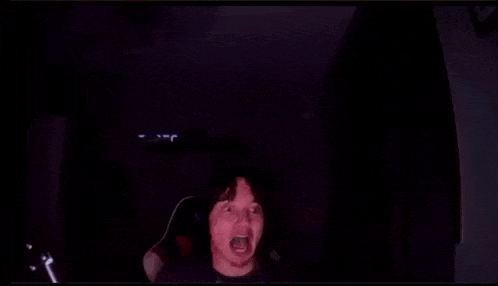 a man is making a funny face in a dark room .