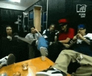 a group of people sitting around a table with a mtv logo on the wall