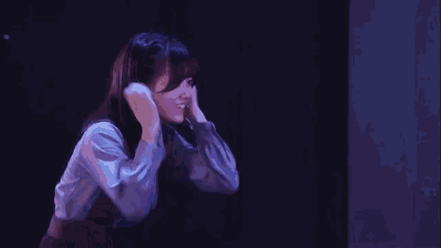 a woman is covering her ears with her hands in the dark