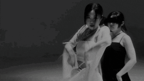 a black and white photo of a woman in a white dress dancing