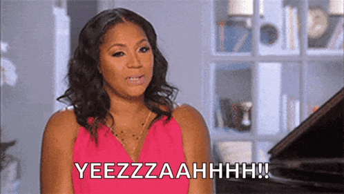a woman in a pink dress is sitting in front of a piano and saying yeezzzaahhhh !