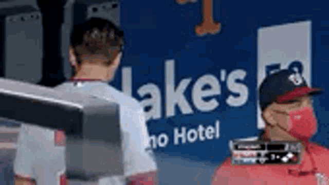a couple of men standing next to each other in front of a sign that says lakes hotel .