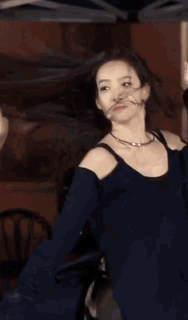 a woman in a black top is dancing with her hair in the air