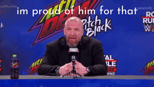 a man with a beard is sitting in front of a mtn dew sign