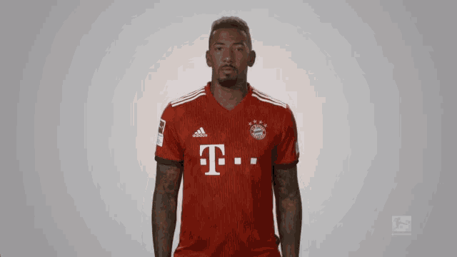 a man wearing a red adidas shirt with the letter t on the front