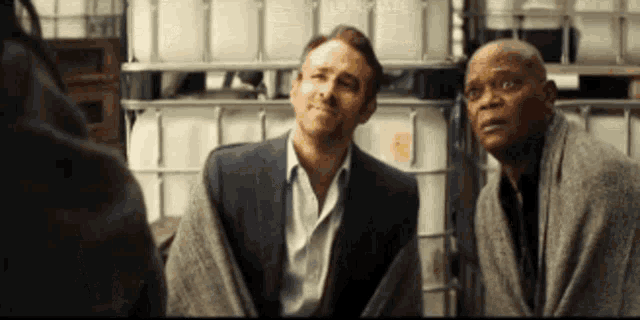 two men are sitting next to each other in front of a warehouse .