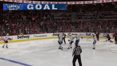 a hockey game is being played in front of a scoreboard that says goal