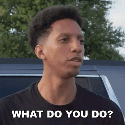a young man is standing in front of a car and asking what do you do