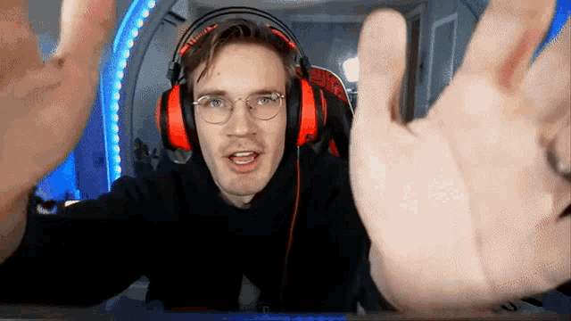 a man wearing headphones and glasses is making a hand gesture