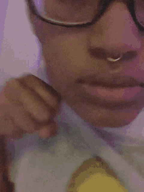a close up of a person 's face with glasses and a nose ring .