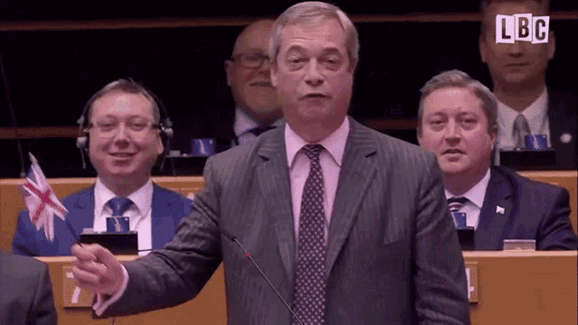 a man in a suit and tie is giving a speech in front of a microphone with lbg written on the bottom