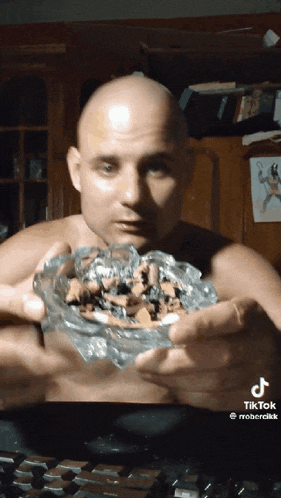 a bald man is holding an ashtray filled with cigarettes