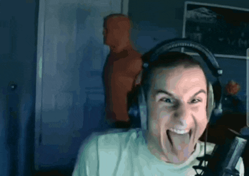 a man wearing headphones is sticking his tongue out in front of a microphone