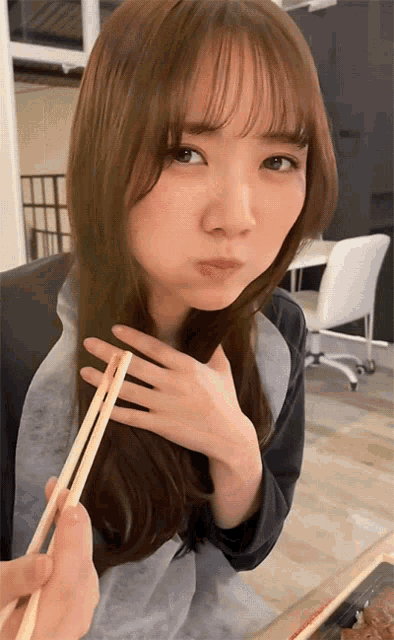 a woman with chopsticks in her hand making a funny face